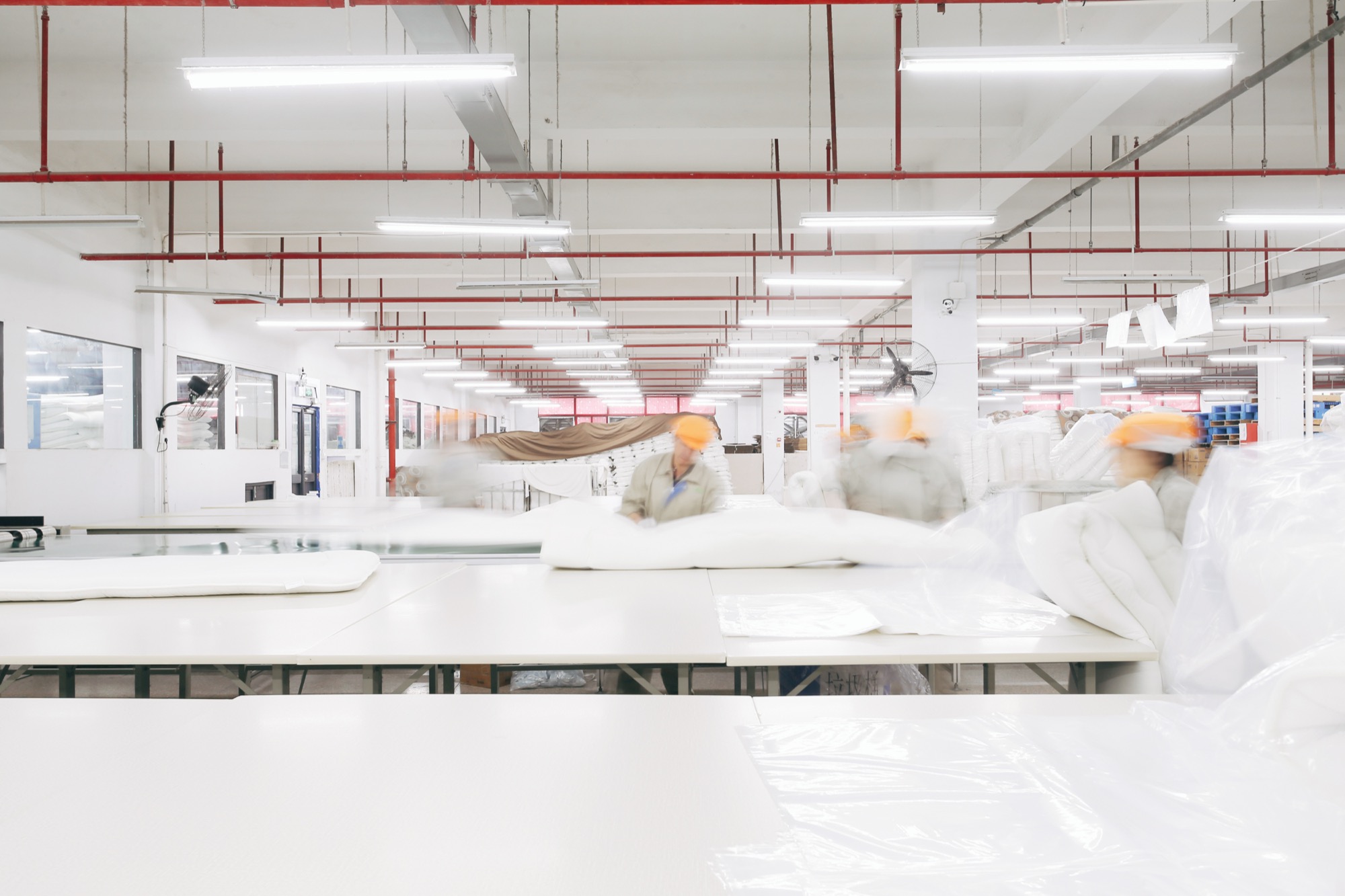 Workers cutting and finishing home textiles on a bright factory floor