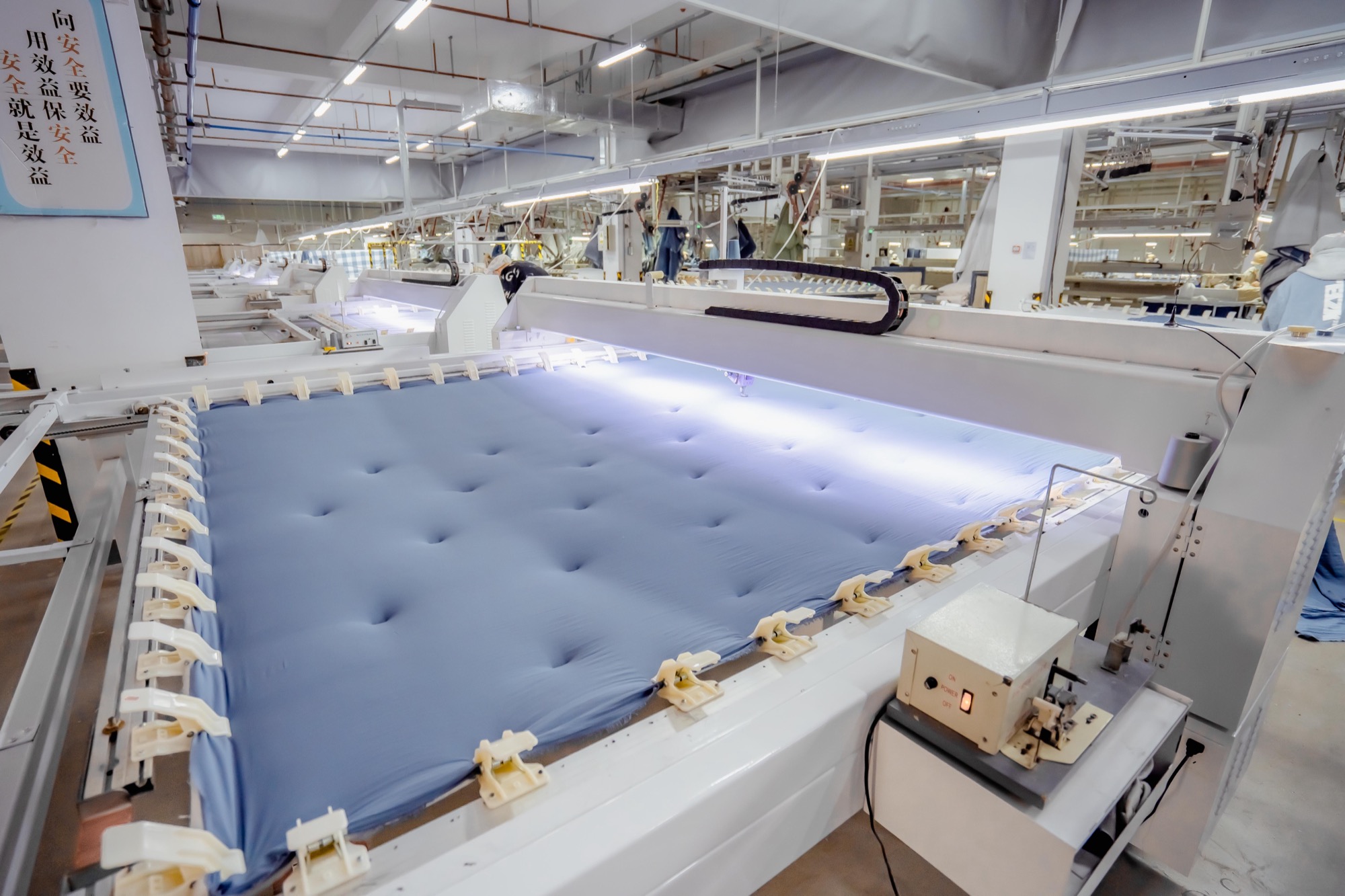 Automated quilting line stitching a finished quilt at an ABS International manufacturing partner