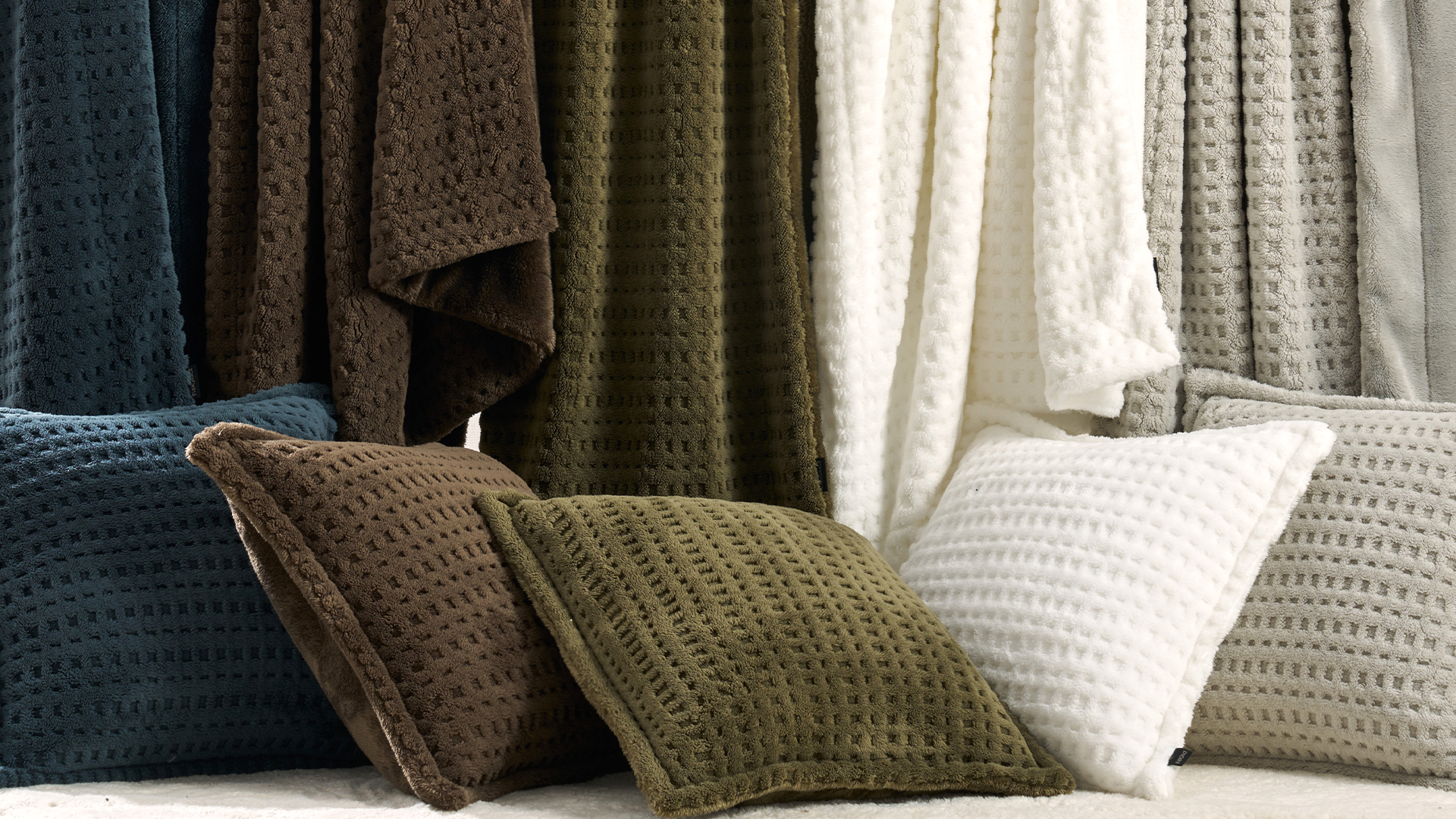 ABS deco pillows — waffle-textured cushions in olive, brown and cream with draped throws behind